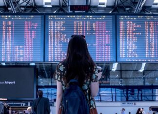 What You Need To Consider Before Boarding Your International Flight Woman looking at departure times at an airport terminal