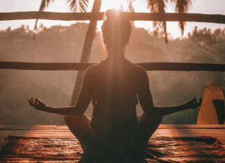 Why You Should Consider a Retreat For Your Next Vacation Woman meditating on a balcony