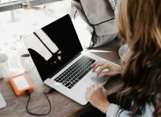 Travel Accessories That Will Make Your Next Trip Easier Woman charging laptop in an airport