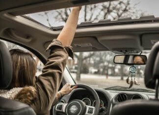 3 Things to Check Before Renting a Car Woman sticking hand out of car sun roof while driving.