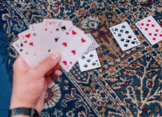 Why You Should Bring a Pack of Cards When Traveling Person Holding Playing Cards on Brown and Black Floral Area Rug