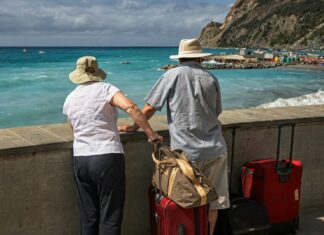 Best Carry-On Luggage For Your Next Vacation Couple with luggage on an Italian beach