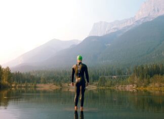 3 Countries for Triathlon Training Triathlete standing in a lake near a mountain
