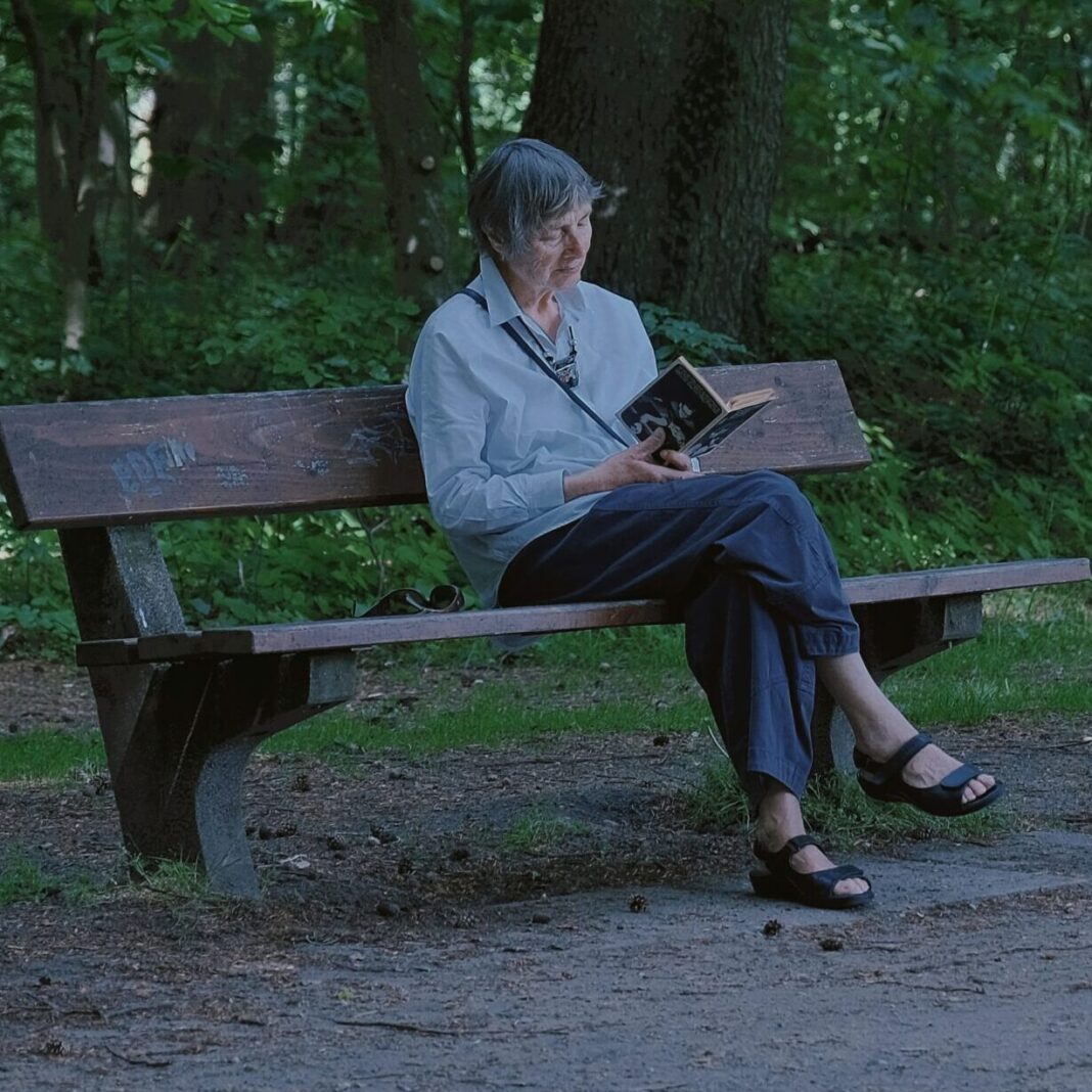 Woman sitting on a bench in a park reading a book