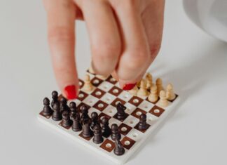 3 Ways to Stay Entertained During Travel Delays Person Playing a Mini Chess on White Surface