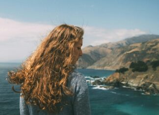 Here’s How to Style Your Wavy Hair on Vacation Woman looking at the ocean.