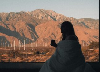 Important Features to Consider When Searching for an Air BnB Woman in a blanket looking out the window to mountains