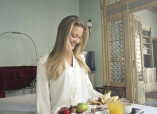 5 Things Keeping in Mind Before Paying For Hotel Breakfast Cheerful woman with breakfast on tray in hotel bedroom