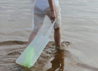Essential Items to Pack in Your Beach Bag Woman in White See Through Dress Walking on Beach