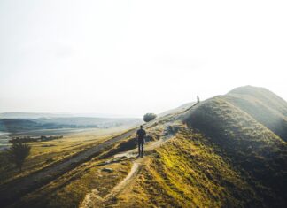 3 Towns in the UK’s Peak District You Have to See Man hiking on a grassy hill
