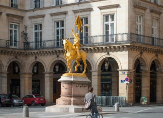 Avoid These Mistakes When Traveling to Paris Man riding a bike Jeanne d’Arc