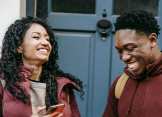 Best Translation Apps for Your Next Vacation Diverse cheerful friends with smartphone laughing near door of building